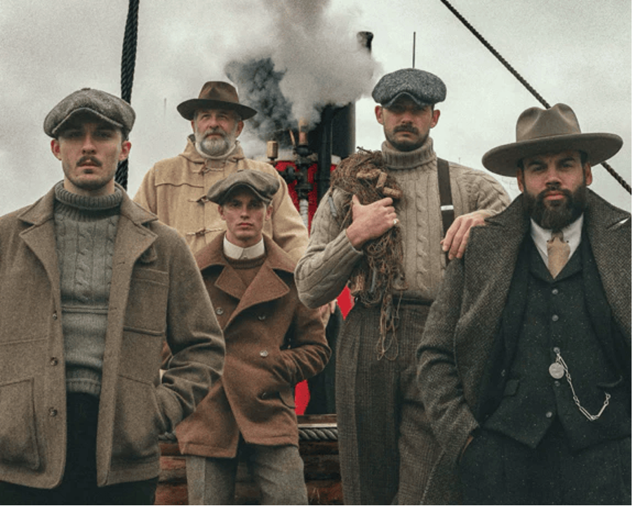 Period-register group in knitwear and tweed before a steamship